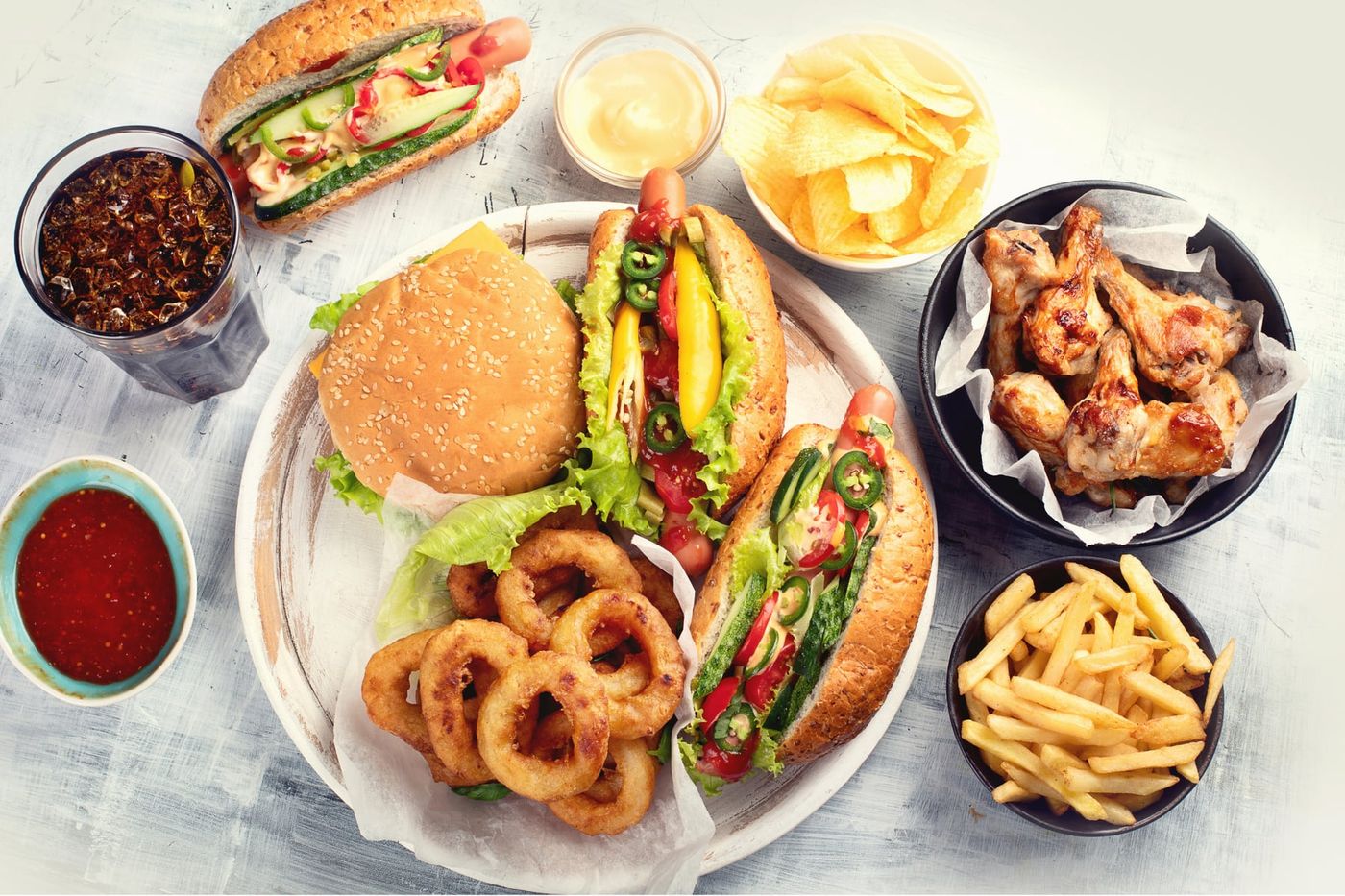 Burgery, hot dogi, skrzydełka, krążki cebulowe i frytki na jasnym stole